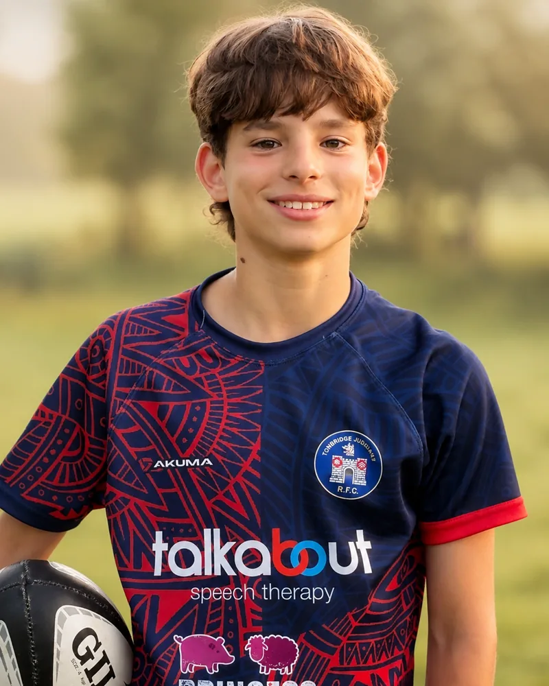 A junior rugby player wearing the Talkabout-sponsored Tonbridge Juddians shirt, holding a rugby ball.